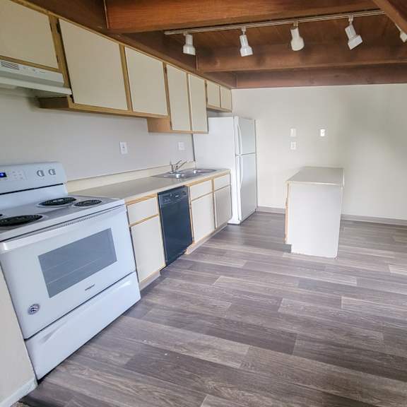 a kitchen with white appliances and a wooden floor