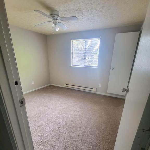 an empty room with a ceiling fan and a window