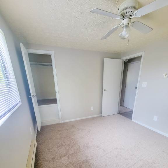 an empty bedroom with a ceiling fan