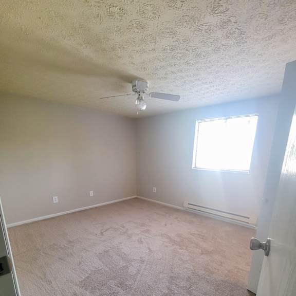 an empty room with a ceiling fan and a window