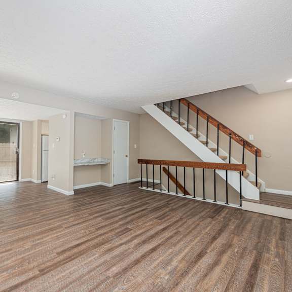the living room and entryway of a house with a hard wood floor and stairs