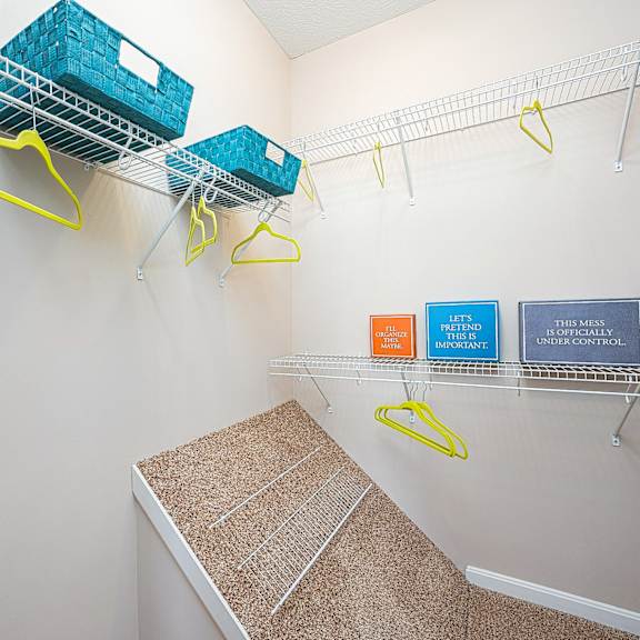 an empty closet with baskets and hooks on the wall