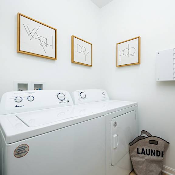 a washer and dryer in a laundry room with three pictures on the wall