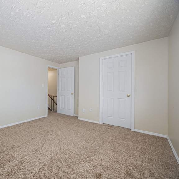 a room with carpeted floor and two doors.