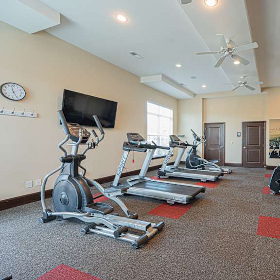 a gym with treadmills and weights and a tv