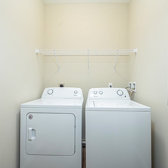 a washer and dryer in a room with a white wall and a closet