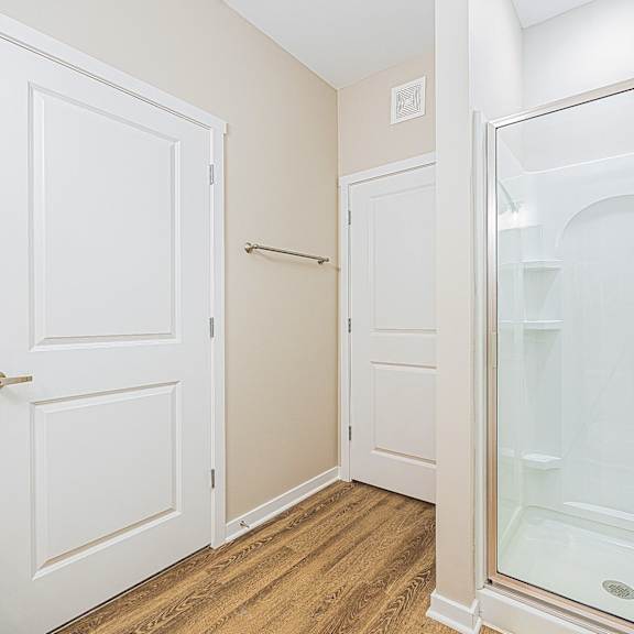 a bathroom with a glass shower and a door to a closet