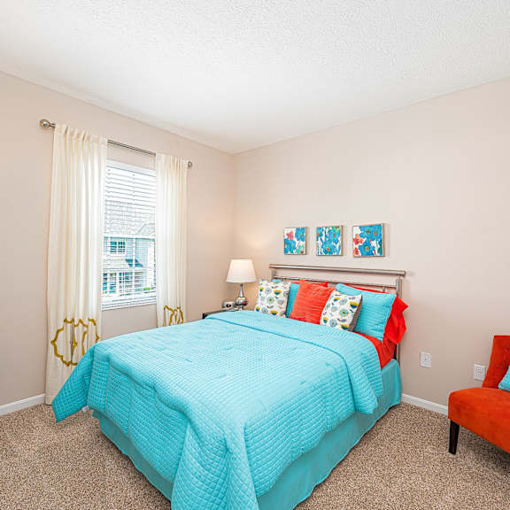 a bedroom with a bed and a chair and a window