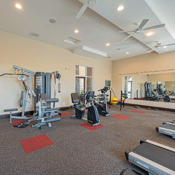 a gym with cardio equipment and weights in a building with white walls