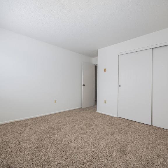 a room with white walls and carpeted floor with a window on the left.