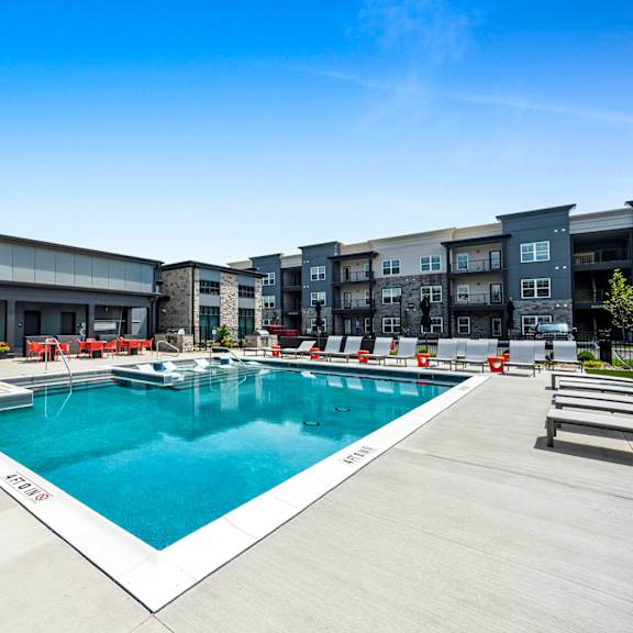 a large outdoor swimming pool with a white edge and a white metal railing.