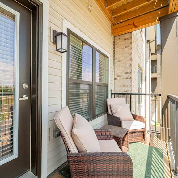 a porch with two wicker chairs and a glass door