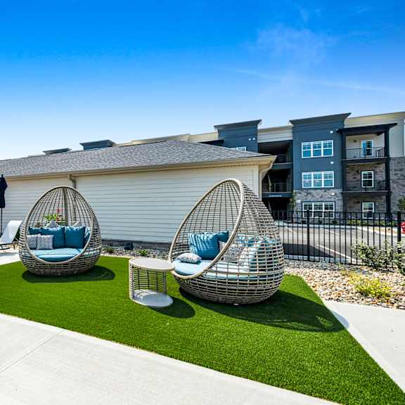 a modern outdoor seating area with white lounge chairs and blue cushions.