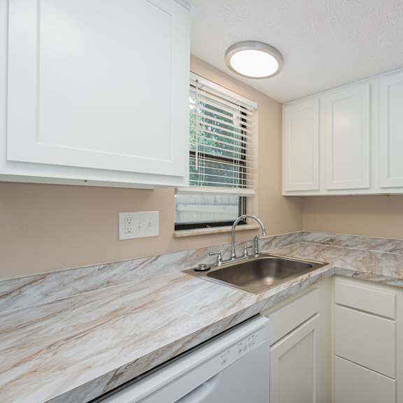 a kitchen with white cabinets and marble counter tops and a sink