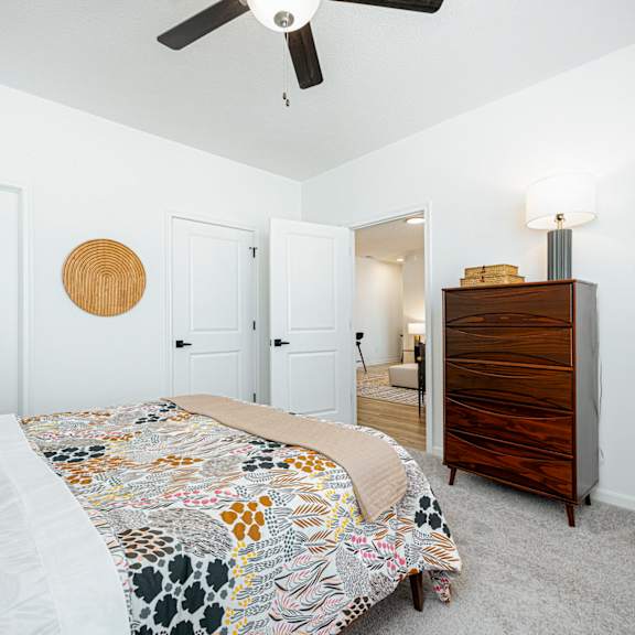 a bedroom with a bed and a dresser and a ceiling fan