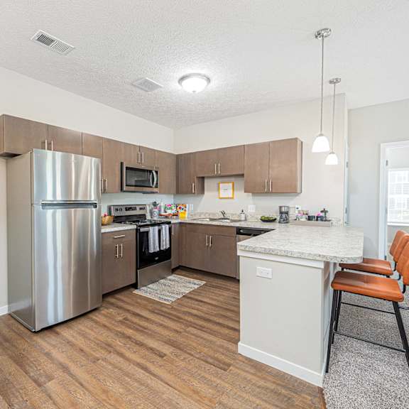 a kitchen and living room with a bar stool and a refrigerator