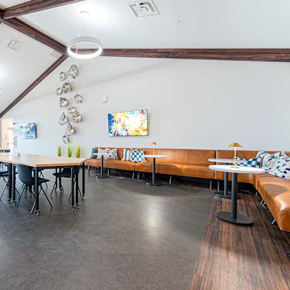 a room with tables and chairs and a long couch.