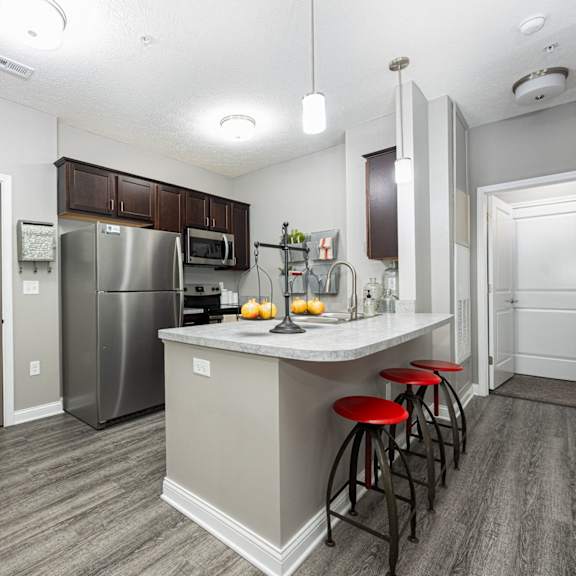 a kitchen with stainless steel appliances and a bar with stools