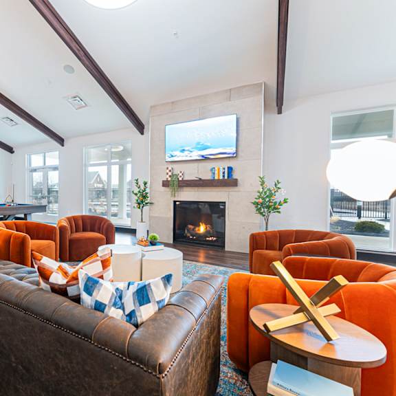 a living room with a brown couch and orange chairs.