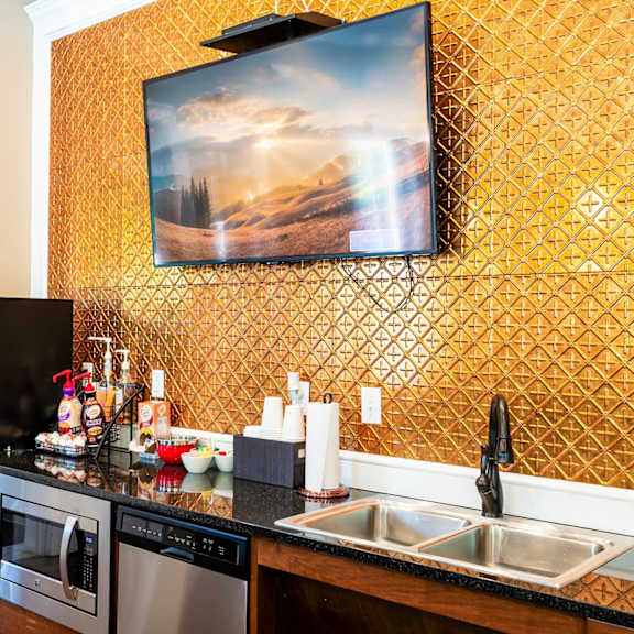 a kitchen with a counter and a sink and a tv on the wall