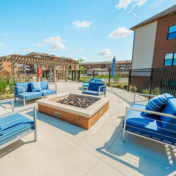 a patio with blue chairs and a fire pit