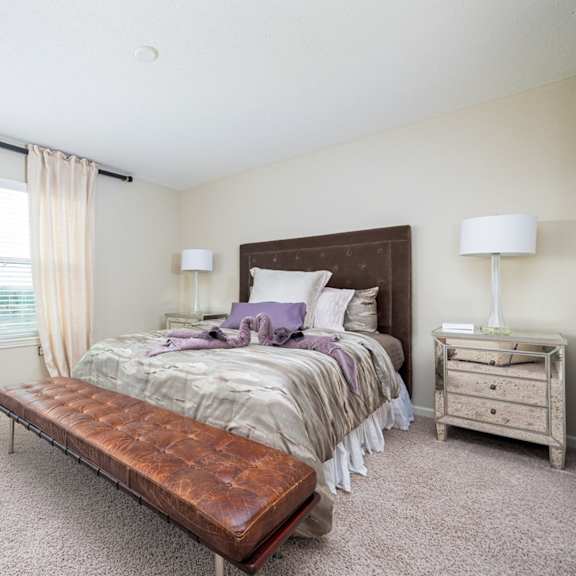 a bedroom with a bed, nightstand, and window with blinds.