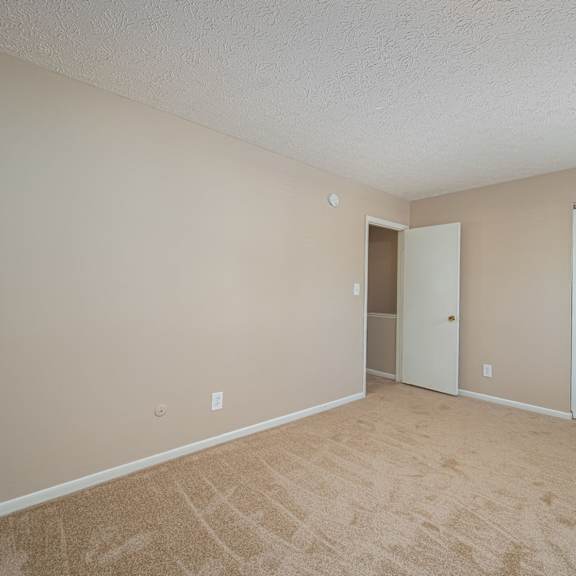 an empty living room with a door to a closet
