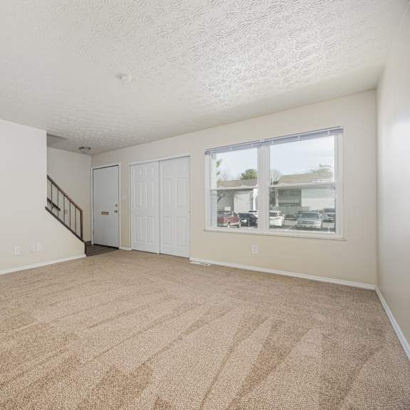 a room with a carpeted floor and a window showing a view of other buildings.