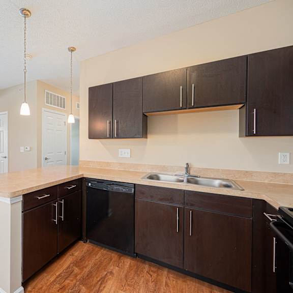 an empty kitchen with wooden floors and black cabinets