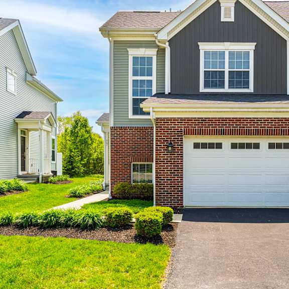 a house with a grey garage door in front of it.
