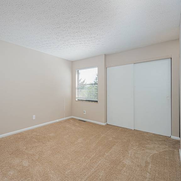 an empty living room with white walls and a window