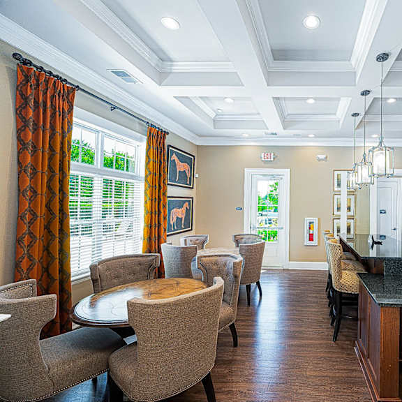 a living room with tables and chairs and a bar