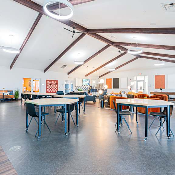 a room with tables and chairs and a ceiling fan.