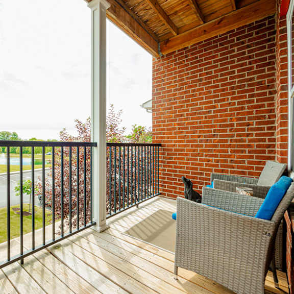a balcony with a brick wall and a wooden deck
