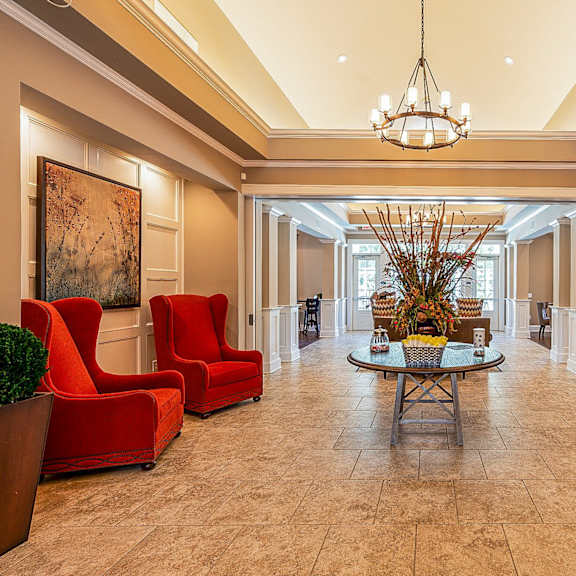a lobby with red chairs and a table and a chandelier