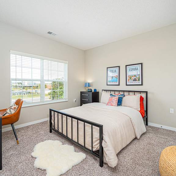 a bedroom with a bed and a desk and a window