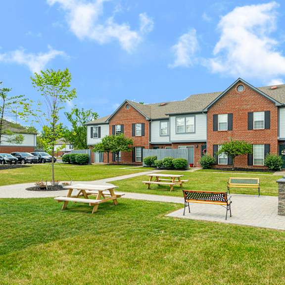 a park with picnic tables in front of a house
