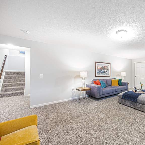 a finished basement with couches and a chair and a table