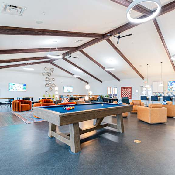 a pool table is in the middle of a room with a couch and a tv.
