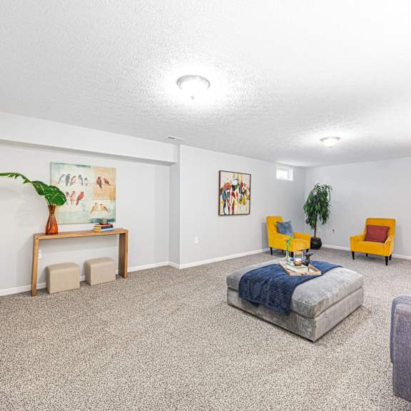 a finished basement with a couch and chairs and a