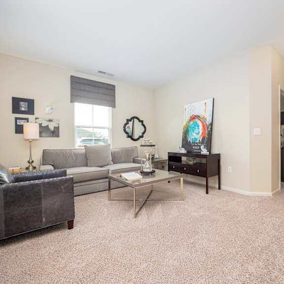 a living room with a grey couch, a coffee table, and a painting on the wall.