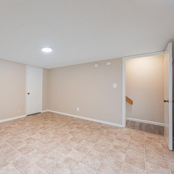 an empty living room with beige walls and a tiled floor