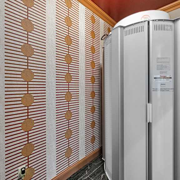 a wall with a brown and white patterned wallpaper and a white fridge.