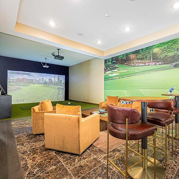 a clubhouse with a large wall mural of a golf course on the wall and chairs