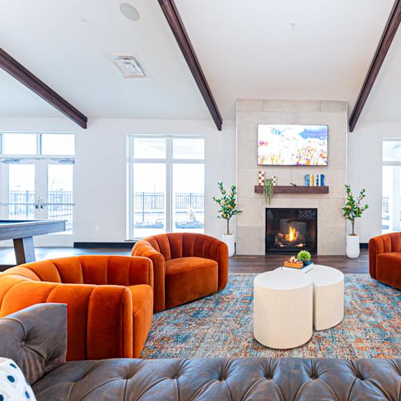a living room with a fireplace and orange chairs.