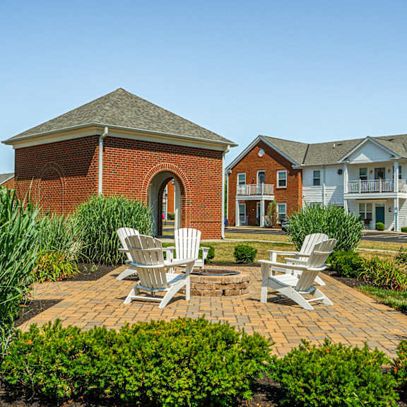 a brick patio with two chairs and a fire pit in front of a brick building