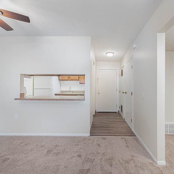 an empty living room and hallway with a ceiling fan
