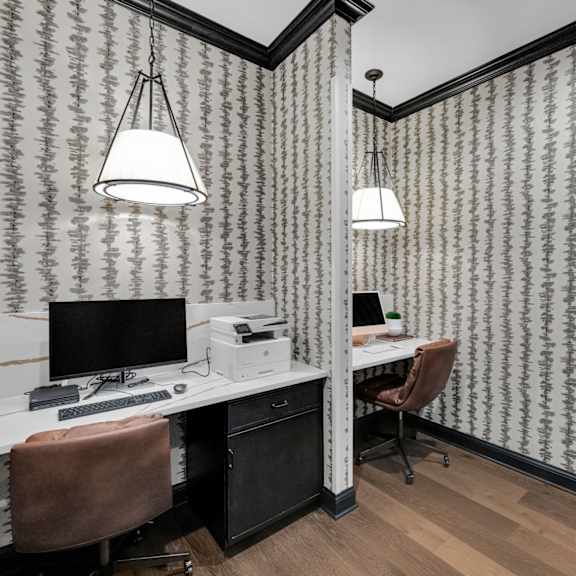a room with a desk and a chair with a patterned wallpaper.