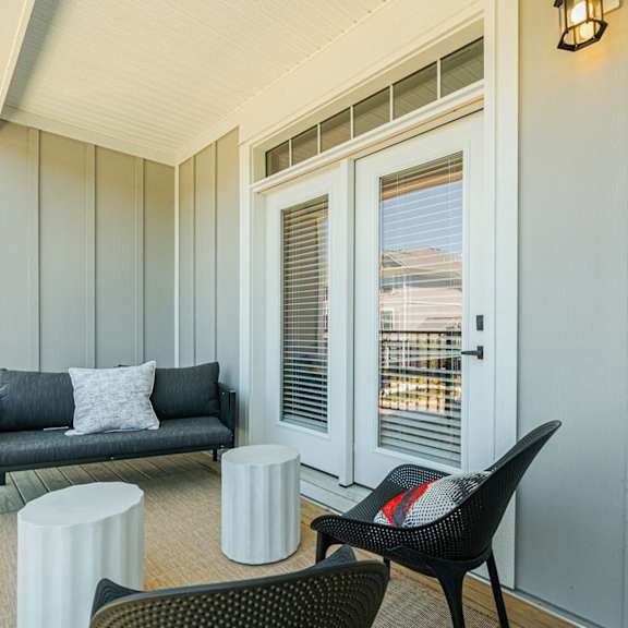 a living room with a couch and chairs and a balcony