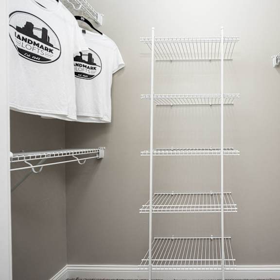 a walk in closet with a wire closet organizer and a shirt hanging on a rack